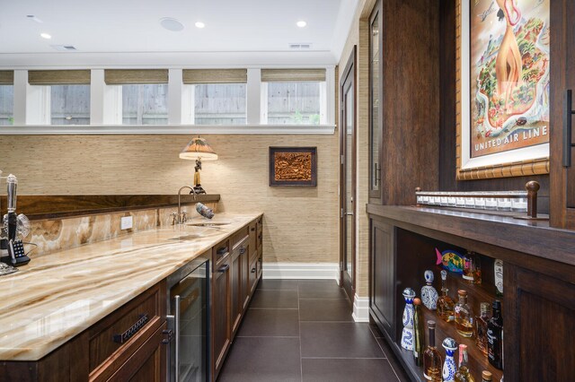 bar featuring wine cooler, sink, dark brown cabinetry, and dark tile patterned floors