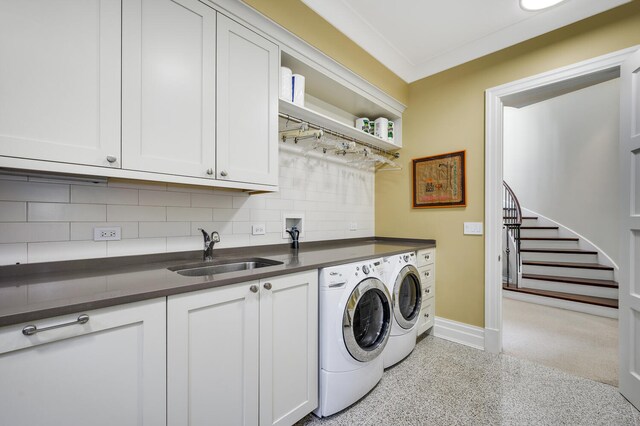 laundry area featuring ornamental molding, cabinets, sink, and washer and clothes dryer