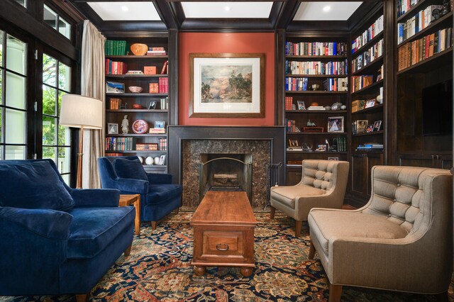 living area featuring beamed ceiling, a high end fireplace, and built in shelves