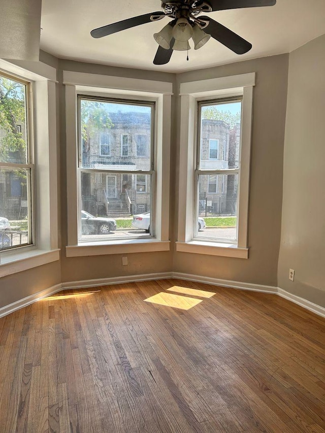 unfurnished room featuring hardwood / wood-style floors, ceiling fan, and a healthy amount of sunlight