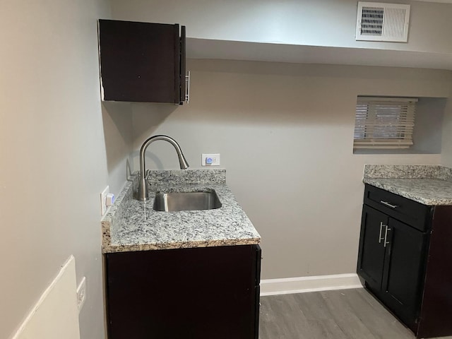 kitchen featuring hardwood / wood-style floors, light stone counters, and sink