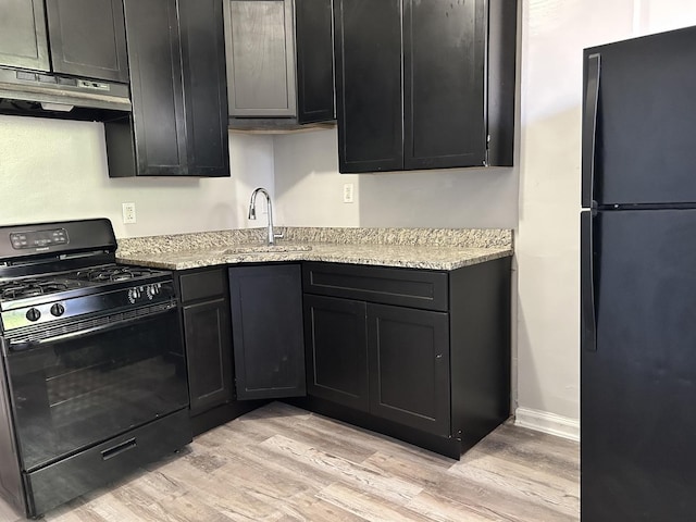 kitchen featuring light stone countertops, sink, light hardwood / wood-style floors, black appliances, and exhaust hood