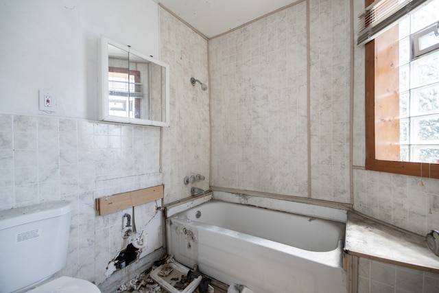 bathroom featuring plenty of natural light, a washtub, toilet, and tile walls