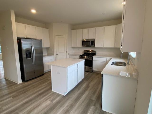 kitchen with a center island, white cabinets, stainless steel appliances, and wood-type flooring