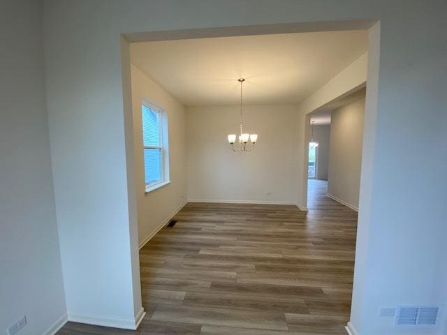 unfurnished dining area with a chandelier and wood-type flooring