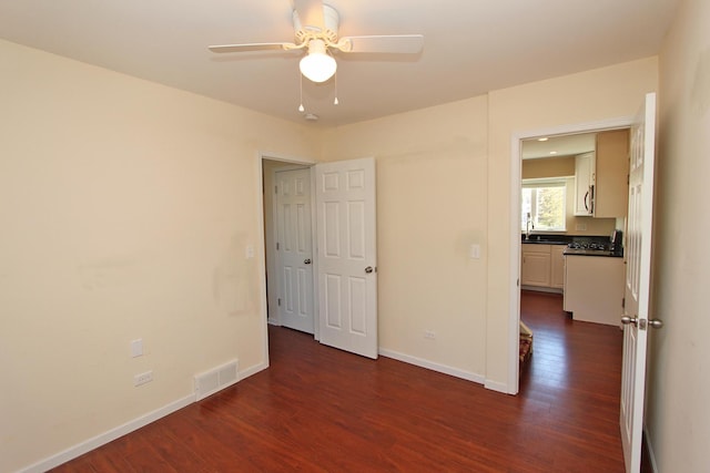 unfurnished bedroom featuring dark hardwood / wood-style floors, ceiling fan, and sink