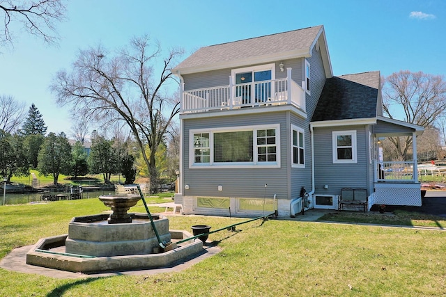 rear view of house with a yard and a balcony