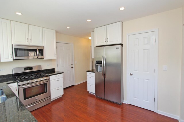 kitchen featuring dark stone counters, dark hardwood / wood-style flooring, white cabinets, and appliances with stainless steel finishes