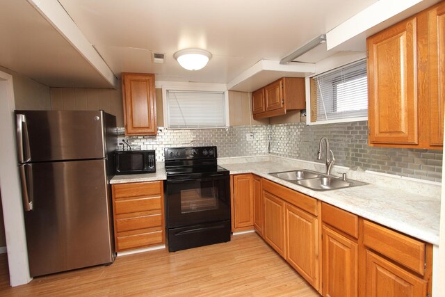 kitchen with sink, light wood-type flooring, black appliances, and backsplash