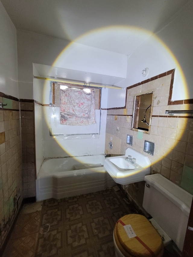 full bathroom with tiled shower / bath combo, tile walls, tile floors, sink, and toilet