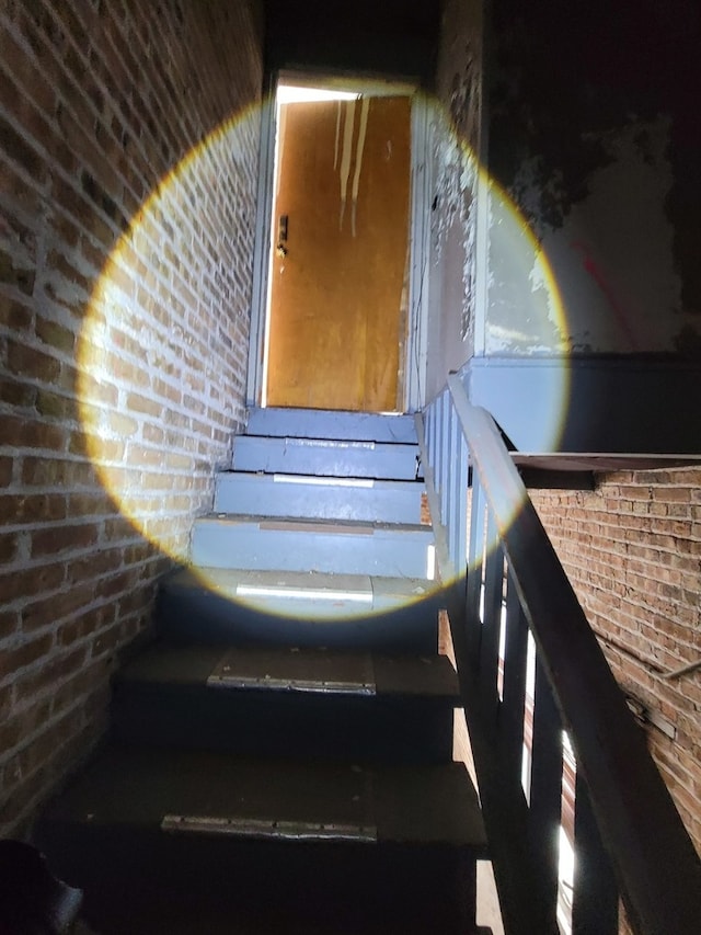 stairway featuring brick wall