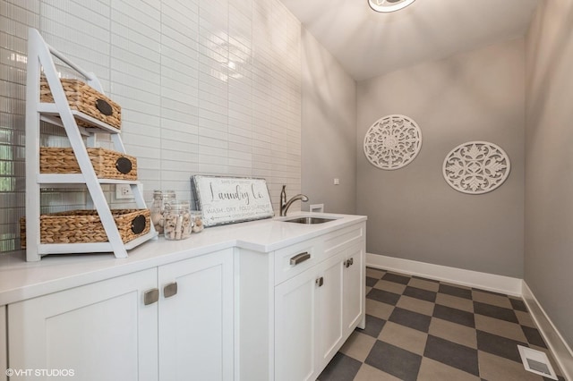 bar with white cabinetry, sink, and tile walls