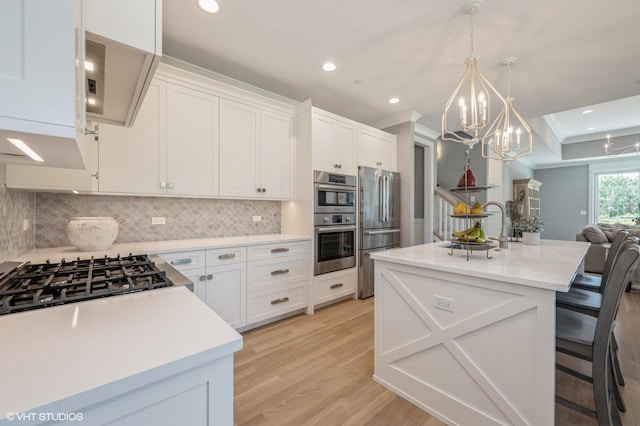 kitchen featuring an island with sink, a breakfast bar, white cabinets, and stainless steel appliances