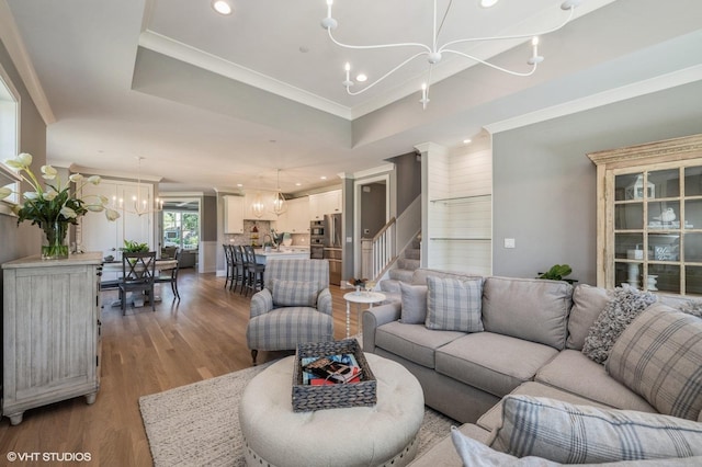 living room featuring a notable chandelier, a tray ceiling, and light hardwood / wood-style flooring