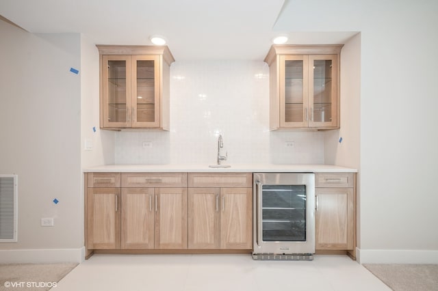 bar featuring sink, beverage cooler, tasteful backsplash, and light tile floors