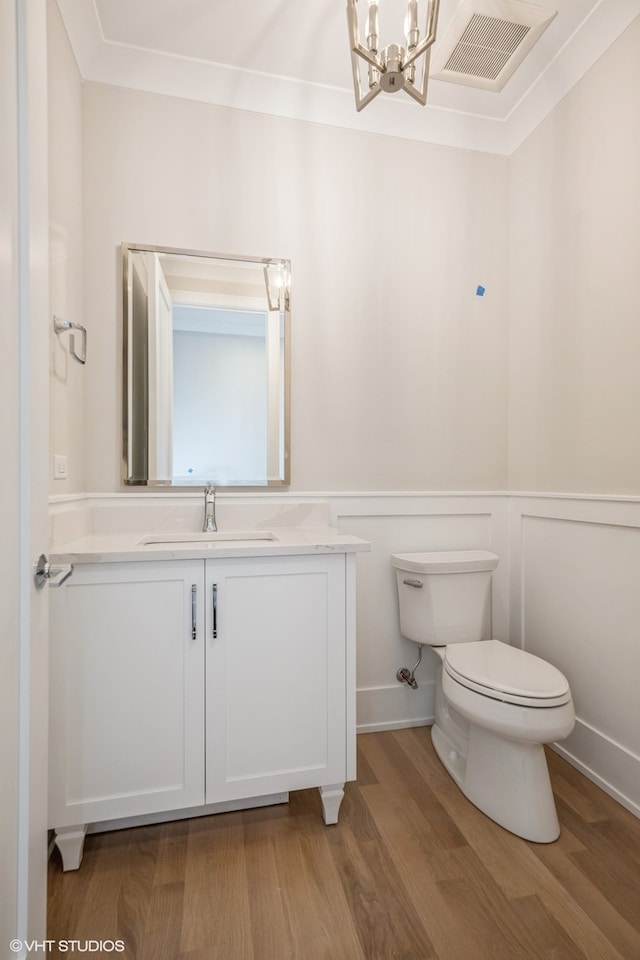 bathroom featuring hardwood / wood-style floors, vanity, toilet, and a chandelier