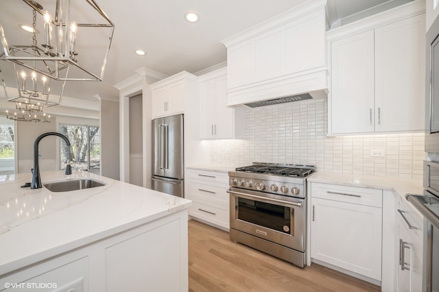 kitchen with white cabinetry, premium appliances, light hardwood / wood-style flooring, sink, and tasteful backsplash