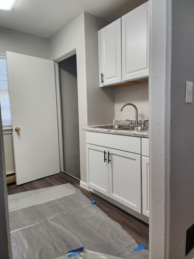 interior space featuring white cabinets, hardwood / wood-style flooring, baseboard heating, and sink