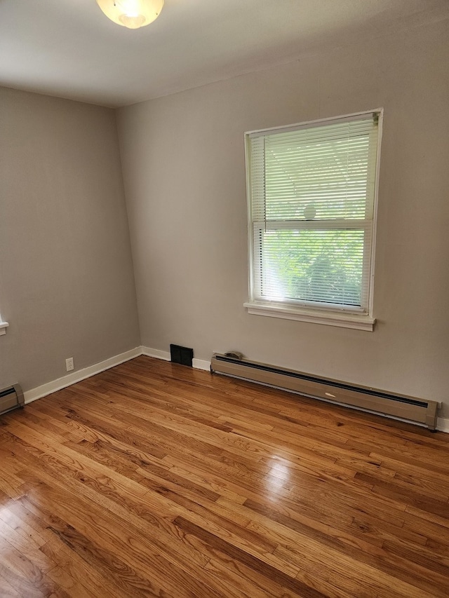 unfurnished room featuring a baseboard radiator and hardwood / wood-style flooring