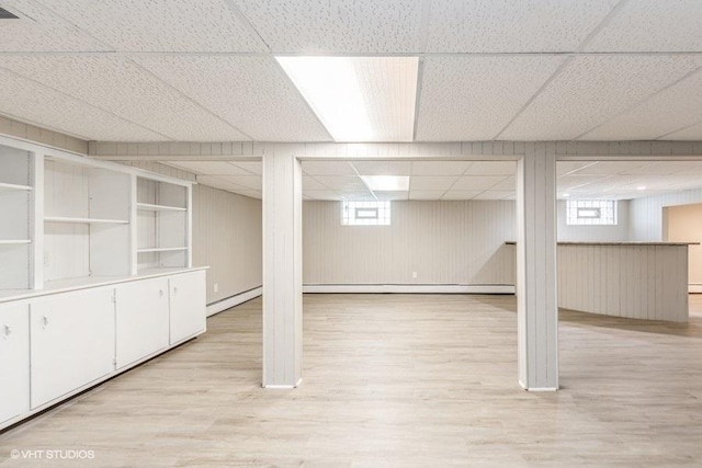 basement featuring a paneled ceiling and light hardwood / wood-style floors