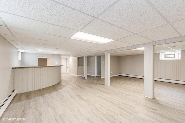 basement with wood-type flooring, a paneled ceiling, and a baseboard radiator