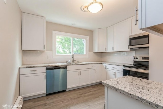 kitchen featuring sink, appliances with stainless steel finishes, tasteful backsplash, light stone counters, and white cabinetry