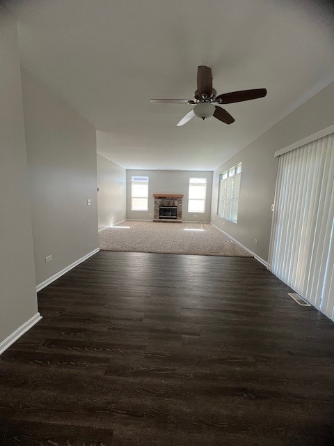 unfurnished living room with ceiling fan and dark wood-type flooring