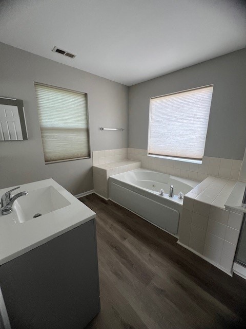 bathroom with a bath, wood-type flooring, and vanity