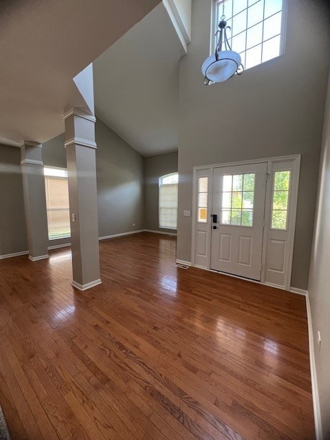 foyer featuring decorative columns, hardwood / wood-style floors, and a towering ceiling