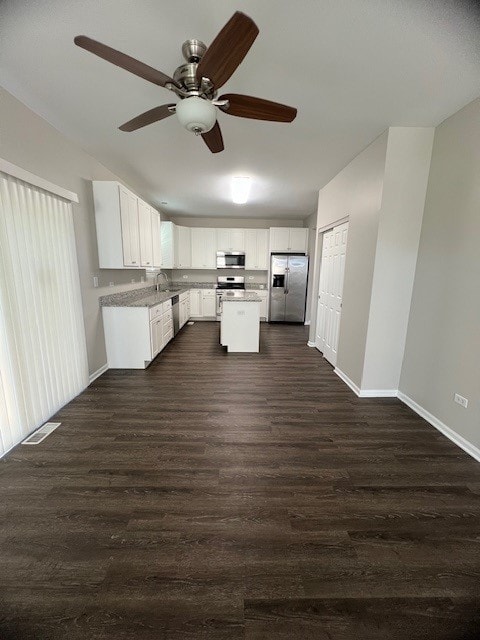 kitchen with appliances with stainless steel finishes, sink, white cabinets, a center island, and dark hardwood / wood-style floors