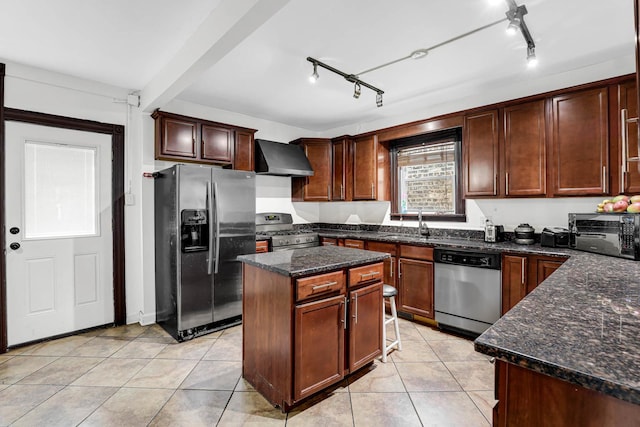 kitchen featuring appliances with stainless steel finishes, wall chimney range hood, light tile patterned floors, dark stone countertops, and a kitchen island