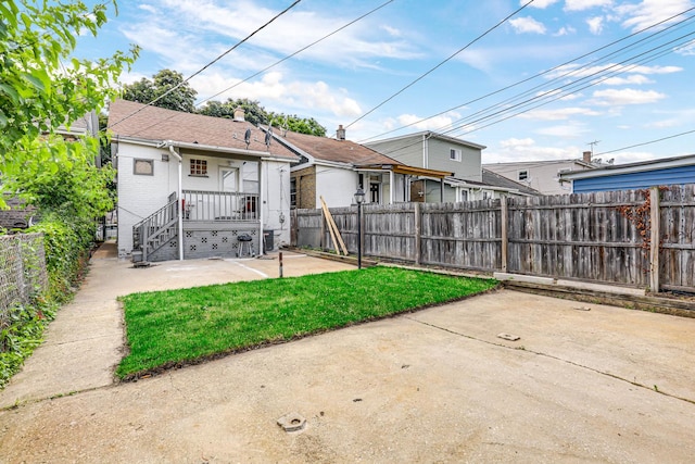 back of house with a lawn and a patio