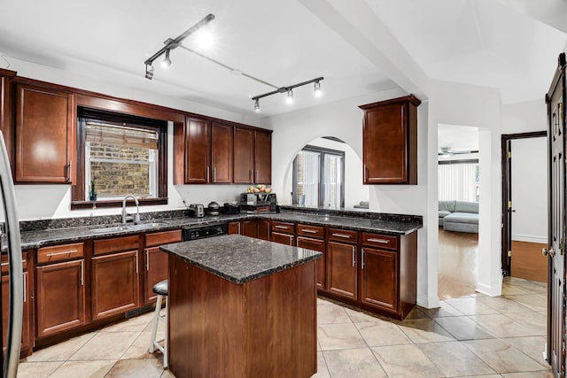 kitchen with dark stone countertops, sink, a kitchen island, and light tile patterned floors