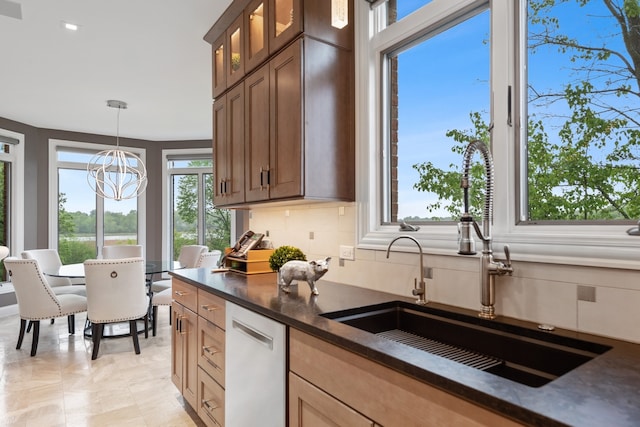 kitchen featuring tasteful backsplash, light tile patterned floors, an inviting chandelier, white dishwasher, and sink