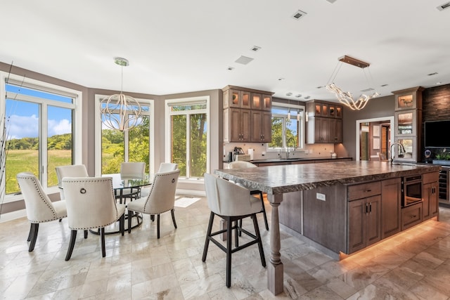 kitchen featuring a center island, built in microwave, hanging light fixtures, and a notable chandelier