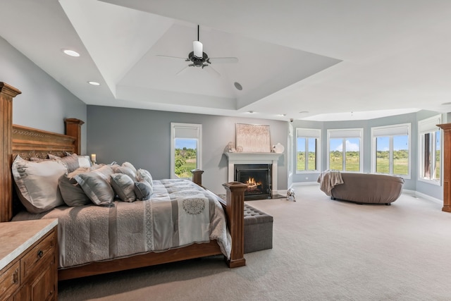 carpeted bedroom featuring a raised ceiling and ceiling fan