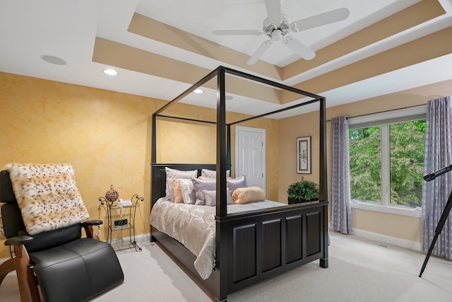 bedroom with ceiling fan, a raised ceiling, and light colored carpet