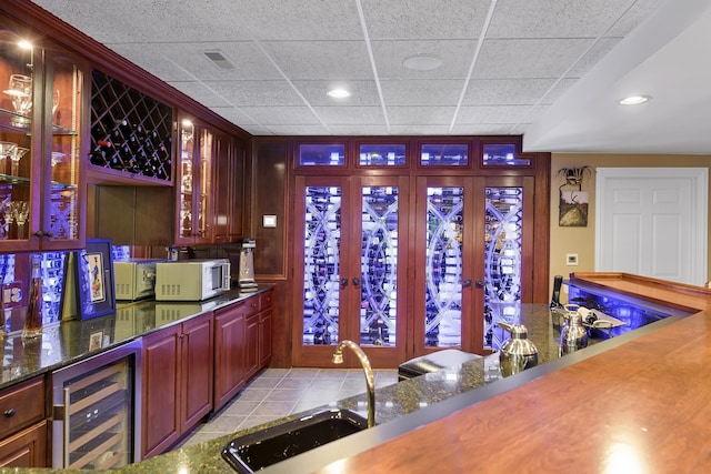 bar featuring a paneled ceiling, sink, french doors, light tile patterned flooring, and wine cooler