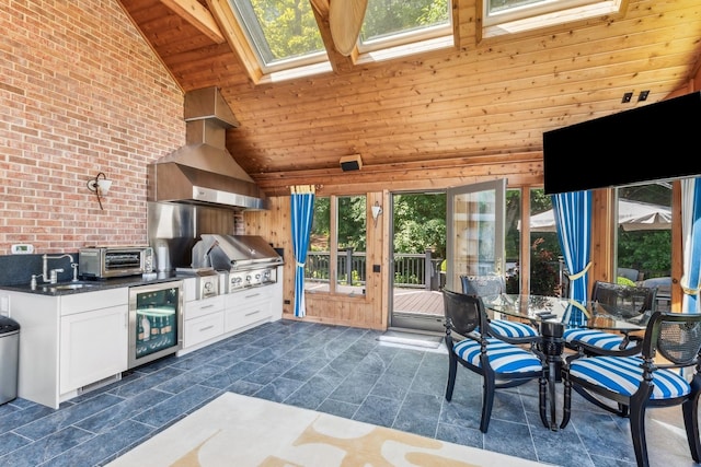 interior space with a skylight, white cabinets, beverage cooler, wood ceiling, and wall chimney range hood