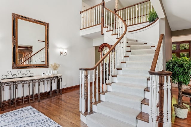 stairs with hardwood / wood-style floors and a high ceiling