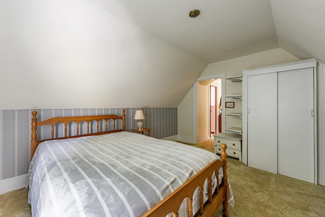 carpeted bedroom with wallpapered walls, vaulted ceiling, and a closet