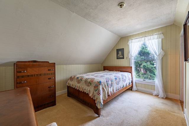 bedroom featuring vaulted ceiling, a textured ceiling, baseboards, and wallpapered walls