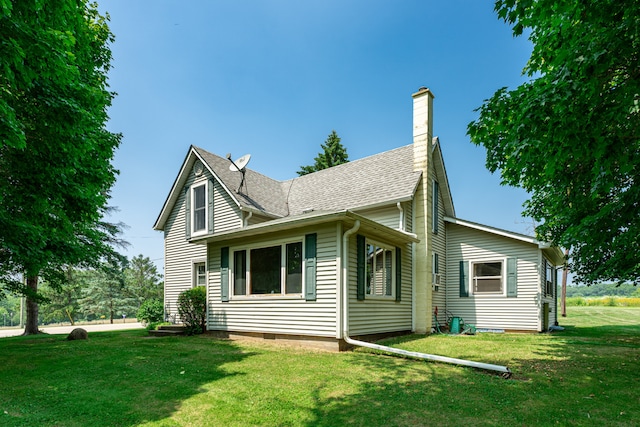 exterior space with a yard, a shingled roof, and a chimney