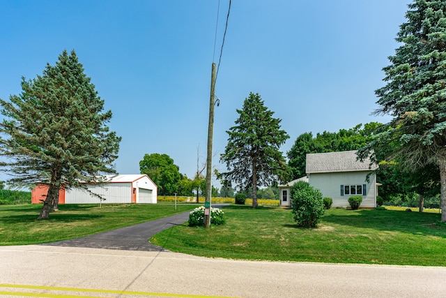 view of front facade with a garage, driveway, an outbuilding, and a front yard