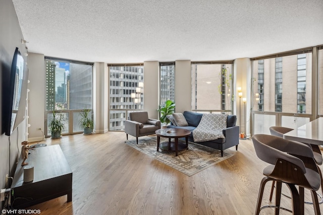 living room with light wood-type flooring, a textured ceiling, and a wall of windows