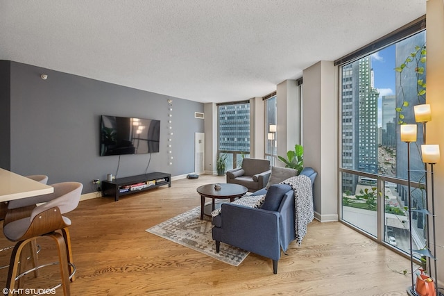 living room with light hardwood / wood-style flooring, a textured ceiling, and a wall of windows