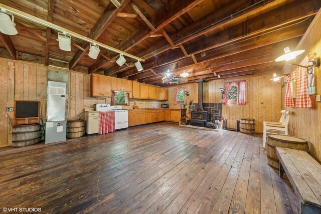 unfurnished living room featuring dark hardwood / wood-style flooring, wood walls, and a wood stove