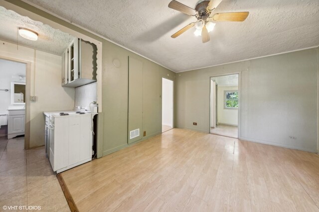 unfurnished living room with ceiling fan, a textured ceiling, and light tile floors