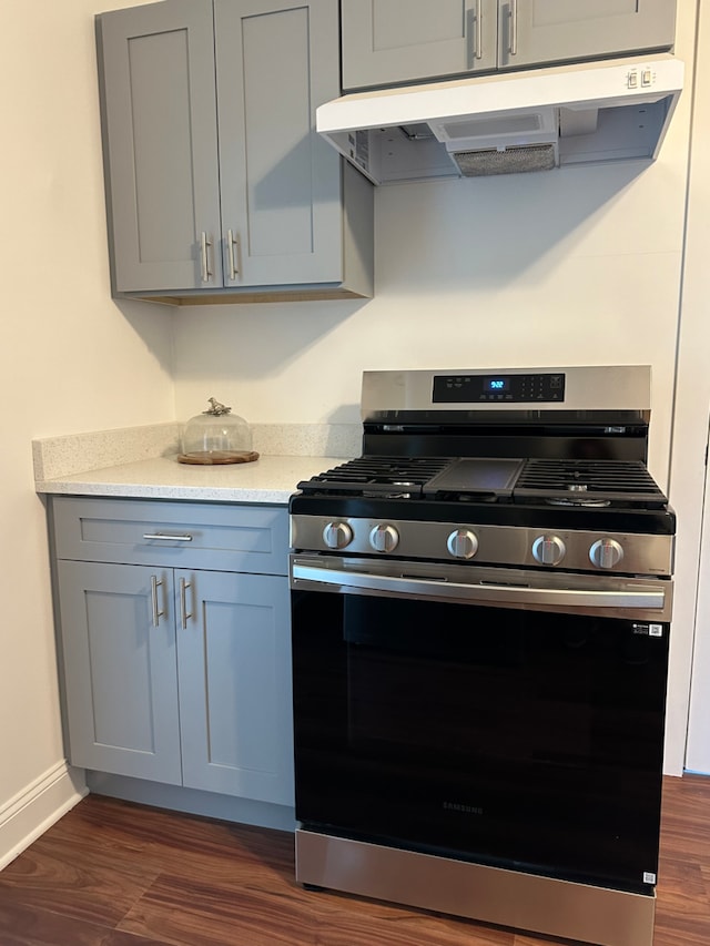 kitchen featuring gas range, light stone countertops, gray cabinets, and dark wood-type flooring