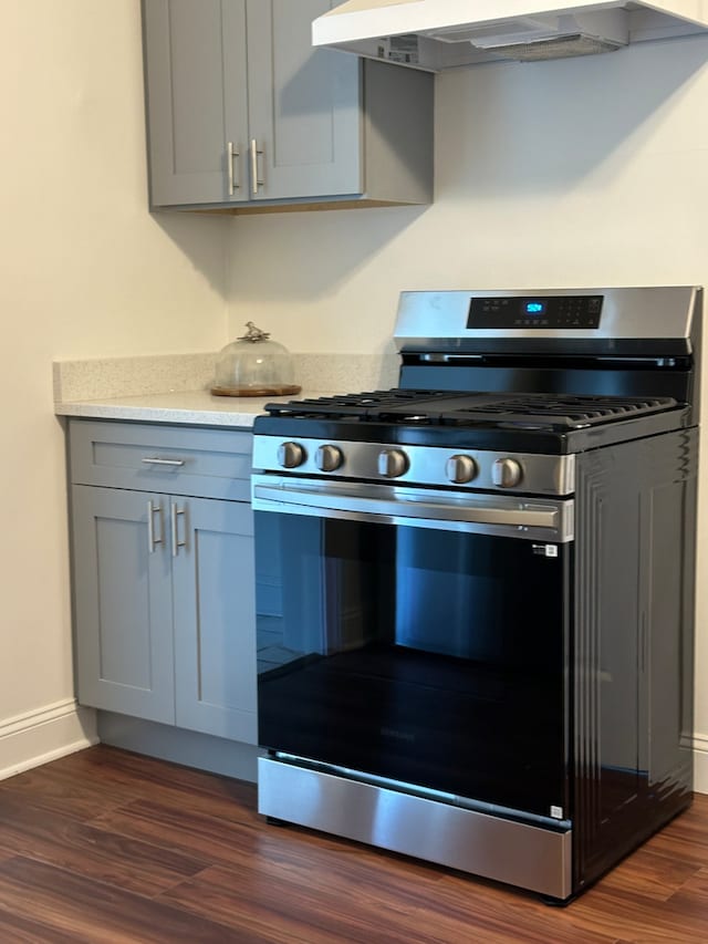 kitchen featuring dark hardwood / wood-style flooring, gas stove, ventilation hood, and gray cabinets